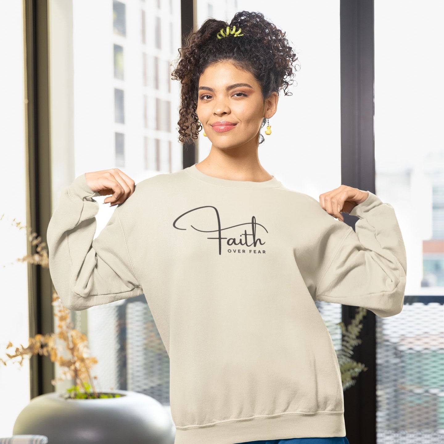 Woman wearing "Faith Over Fear" sweatshirt in Sand