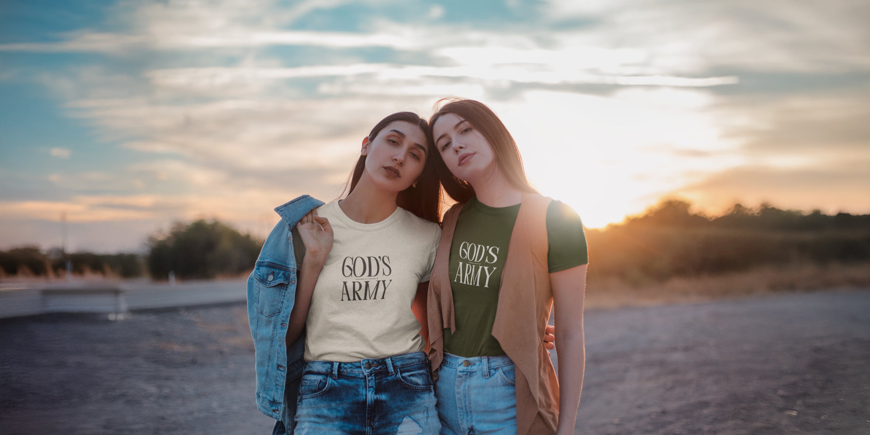 Two women wearing 'Gods Army' t-shirts standing on a beach at sunset.