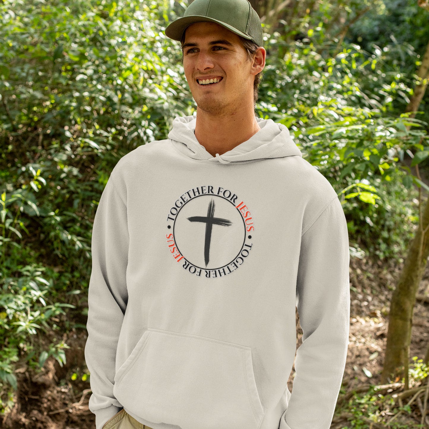 Person wearing a beige colored hoodie with a cross design in a forest setting