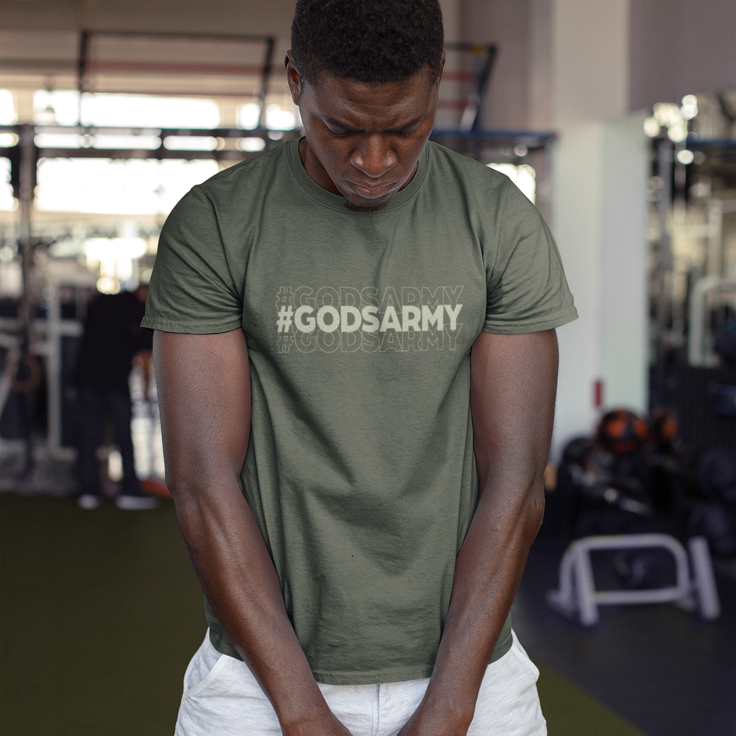 Person lifting a kettlebell wearing a '#GODSARMY' t-shirt in a gym setting