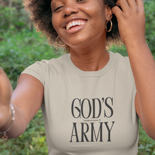 Woman wearing a beige t-shirt with 'GOD'S ARMY' text outdoors.
