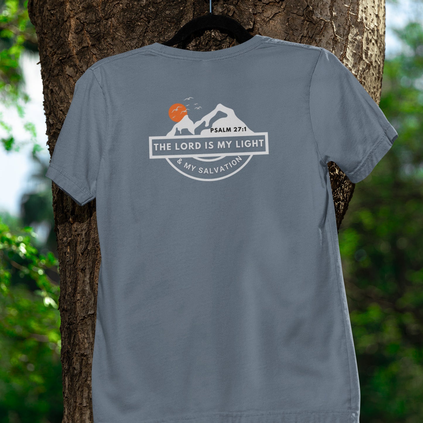 Gray t-shirt with a motivational design on the back, hanging on a tree