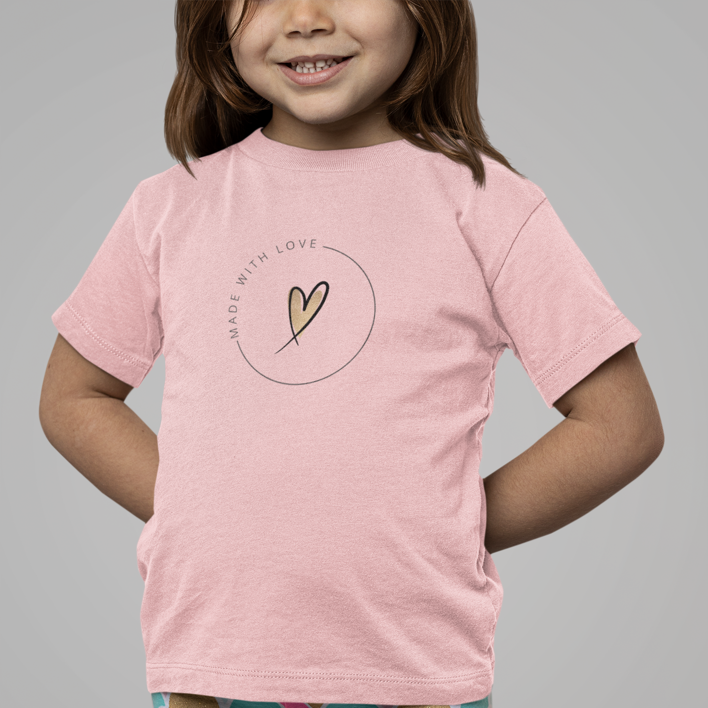 Child wearing a pink t-shirt with a heart design and colorful leggings on a gray background